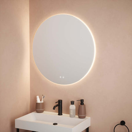 Round illuminated mirror above a sink with toiletries on a beige wall