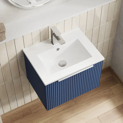 Bathroom vanity with white sink and blue striped cabinet against tiled wall.