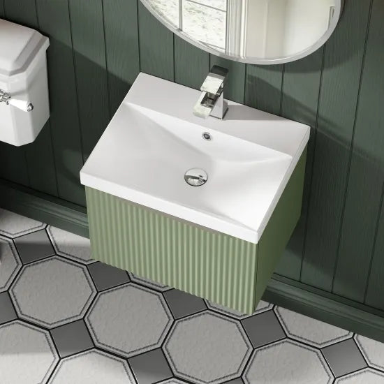 Bathroom with a white sink on a green cabinet against a dark green wall.