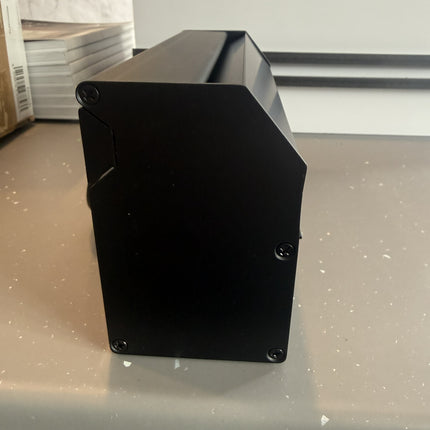 Black rectangular object on a light gray surface with a white background